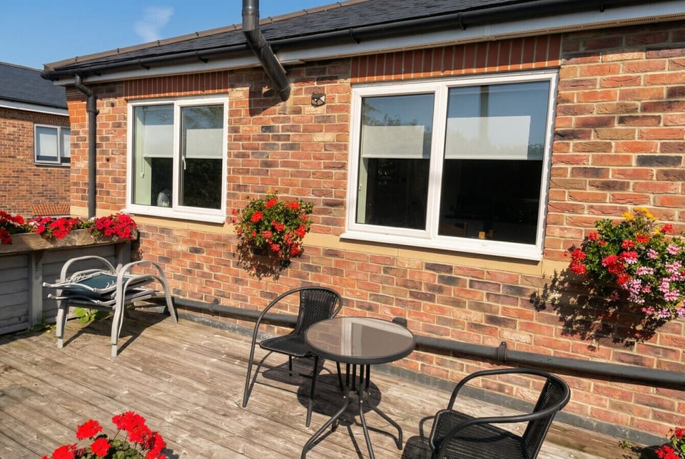 The decked patio catches the afternoon sun beside flowering hanging baskets all season long.