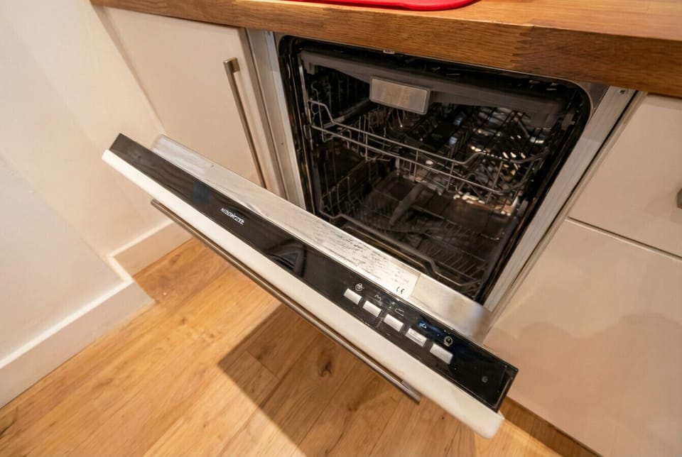 Full-size dishwasher tucked under the oak worktop keeps cleanup effortless after big group meals.