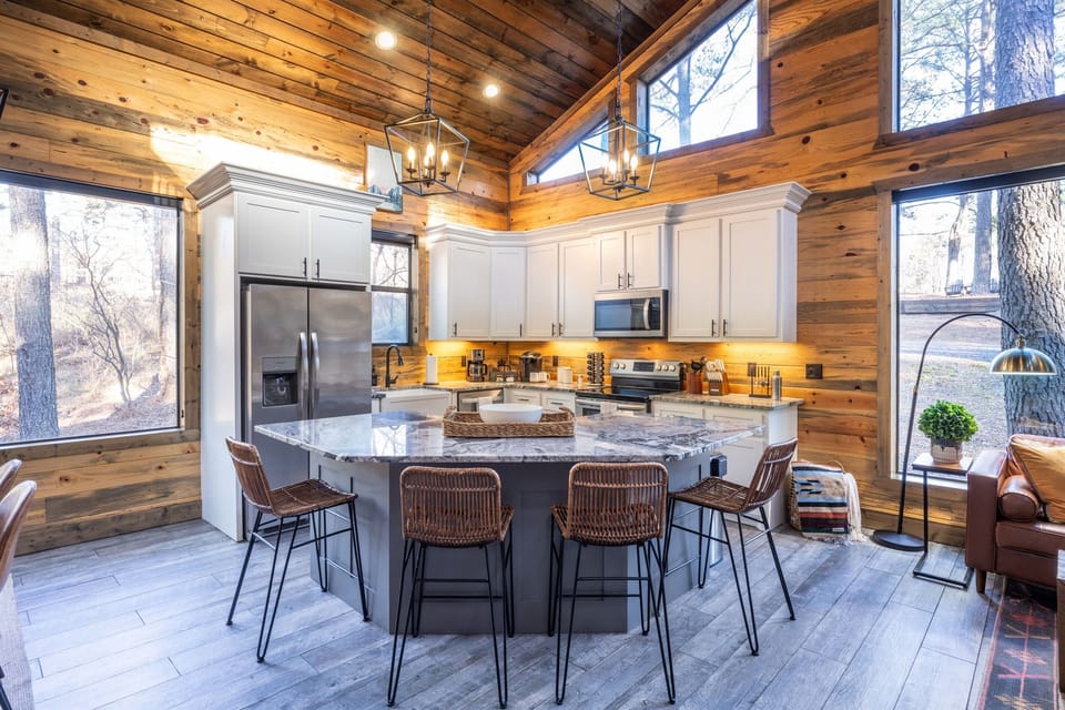 This well-equipped kitchen boasts white cabinetry, modern appliances, and a central island with wicker seating, perfect for socializing while preparing meals. The kitchen is stocked with spices, coffee, and plenty of equipment to cook epic meals!
