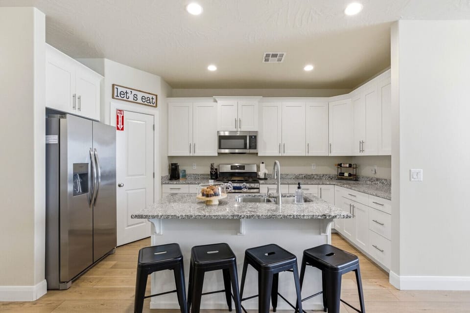 Kitchen: Modern space with sleek countertops, stylish stools, and a fun `let`s eat` vibe!