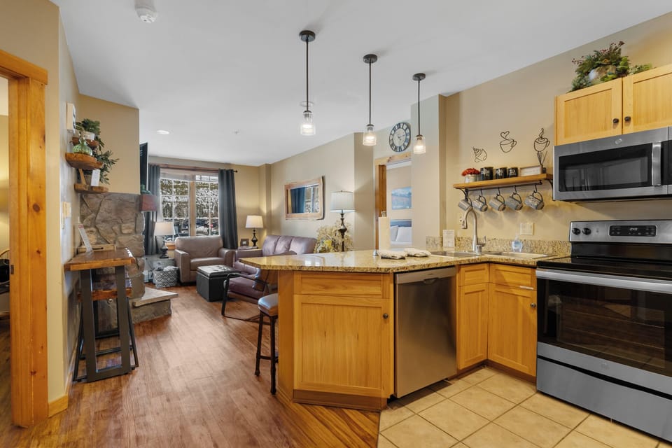 Relax in your open-concept living space with fully equipped kitchen, cozy fireplace, and warm mountain lodge atmosphere.