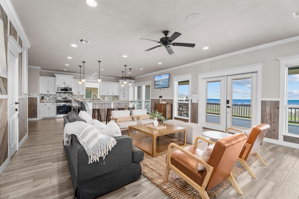 Open living area with sofa, accent chairs, and connected kitchen space