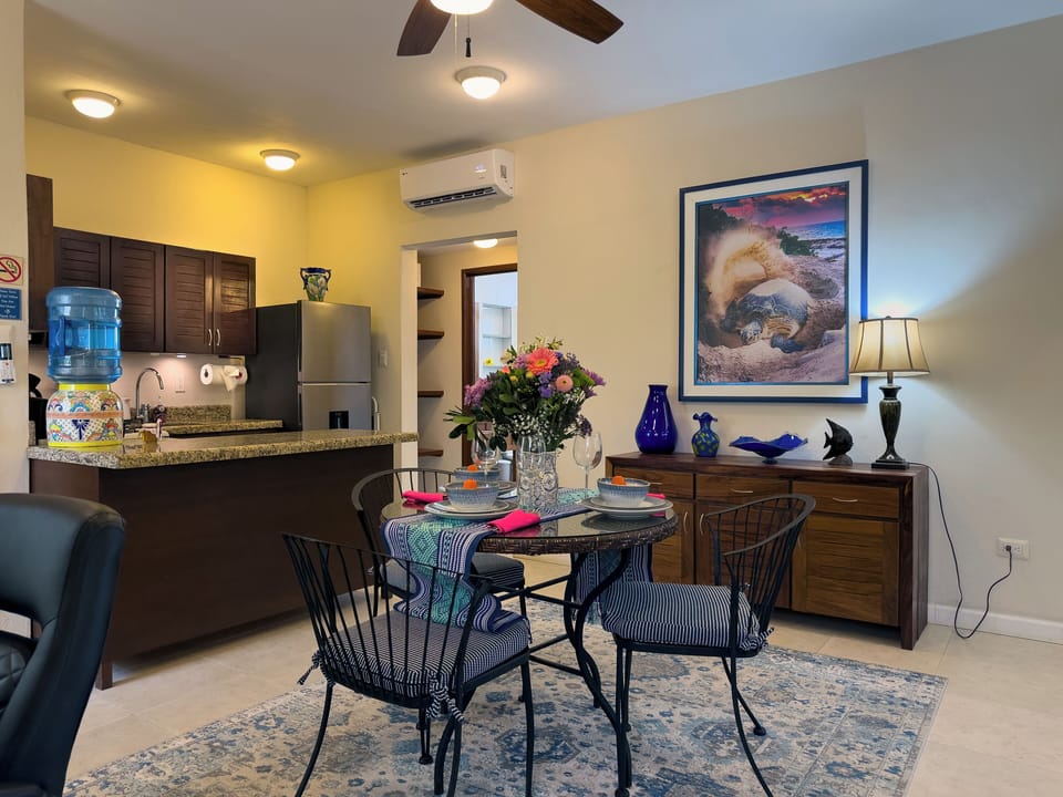 Abbey del Sol Apt 6 – Dining Area & Kitchen (Open Concept) - Open living/dining space with dining table for 3, ceiling fans, and an adjacent full kitchen—comfortable for meals and relaxing indoors.
