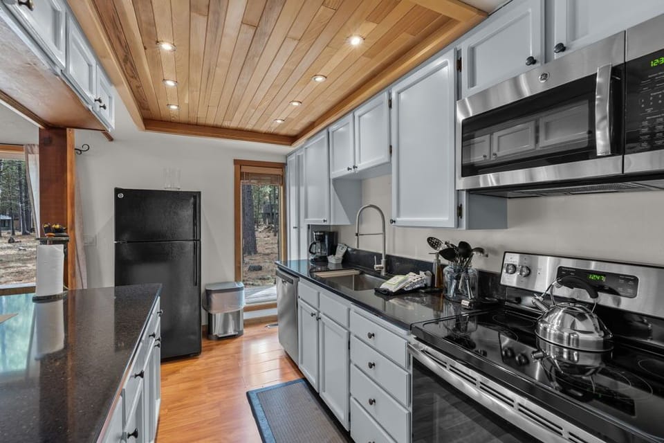 Your fully equipped kitchen awaits with stainless steel appliances, granite counters, and warm wood ceiling for memorable meal prep.