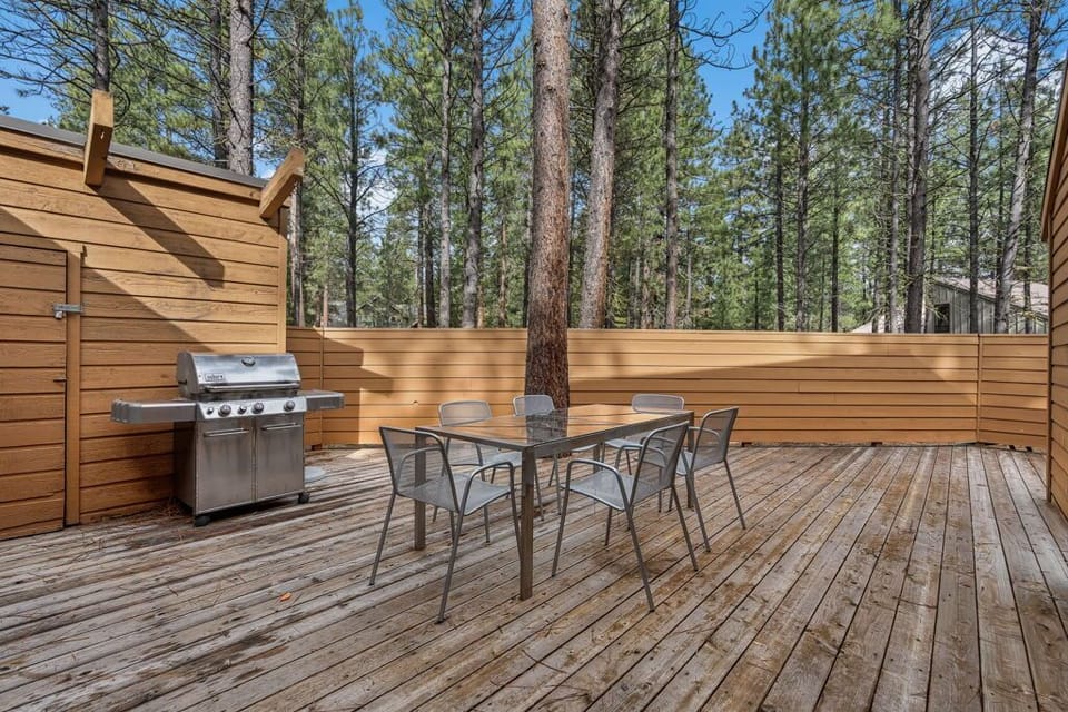 Your private deck awaits with a gas grill and dining table, perfect for forest-view meals under towering pines.