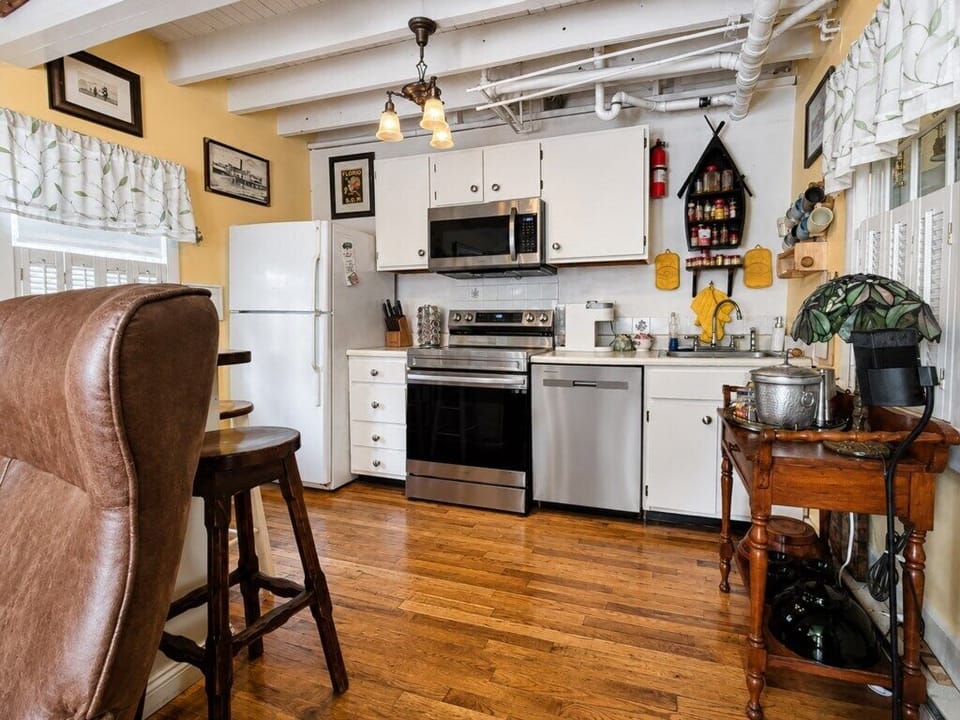 Wide view of the kitchen with stainless appliances, hardwood floors and plenty of original character.