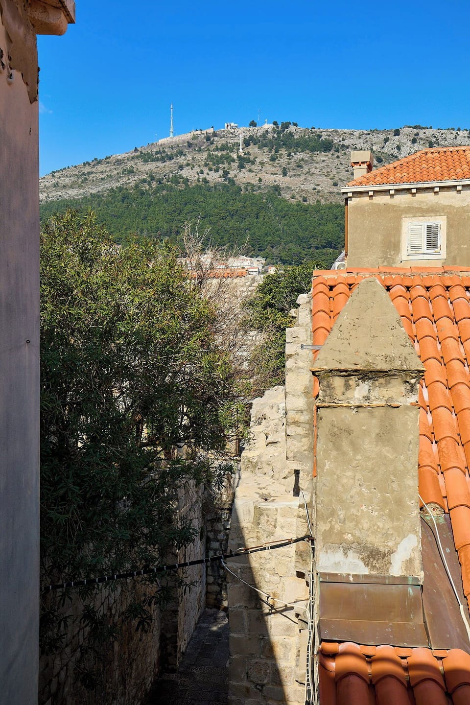 Step into a world of historic charm, where narrow stone alleys lead to stunning views of the lush green hills overlooking Dubrovnik.