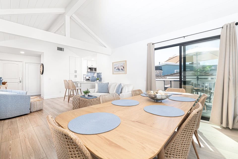 Bright open-concept living and dining area with vaulted ceilings and coastal décor
                