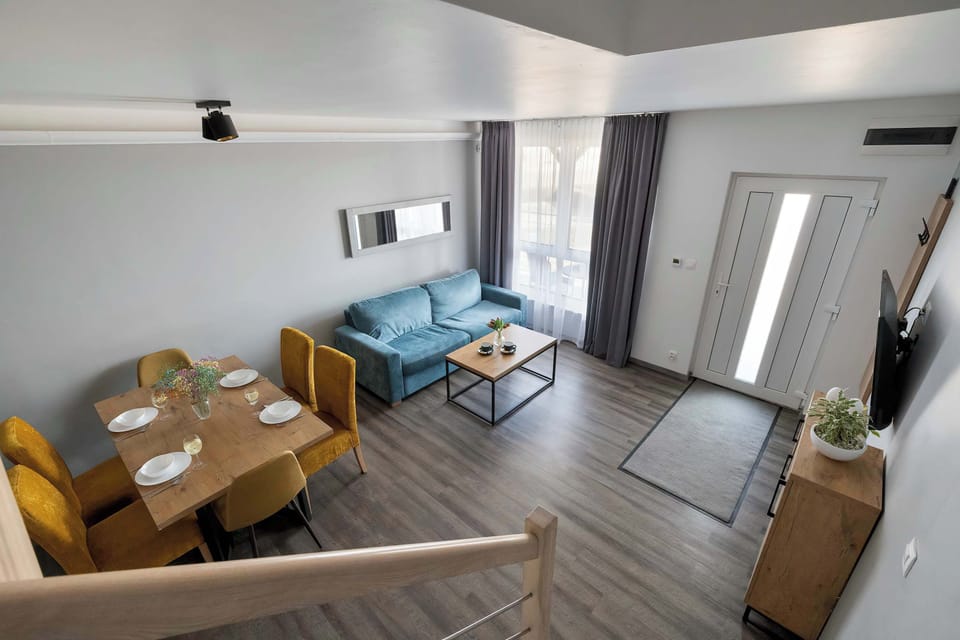A high-angle view from the stairs looks down onto the entire living and dining area. This perspective shows how the open layout connects the entrance to the relaxation zones.