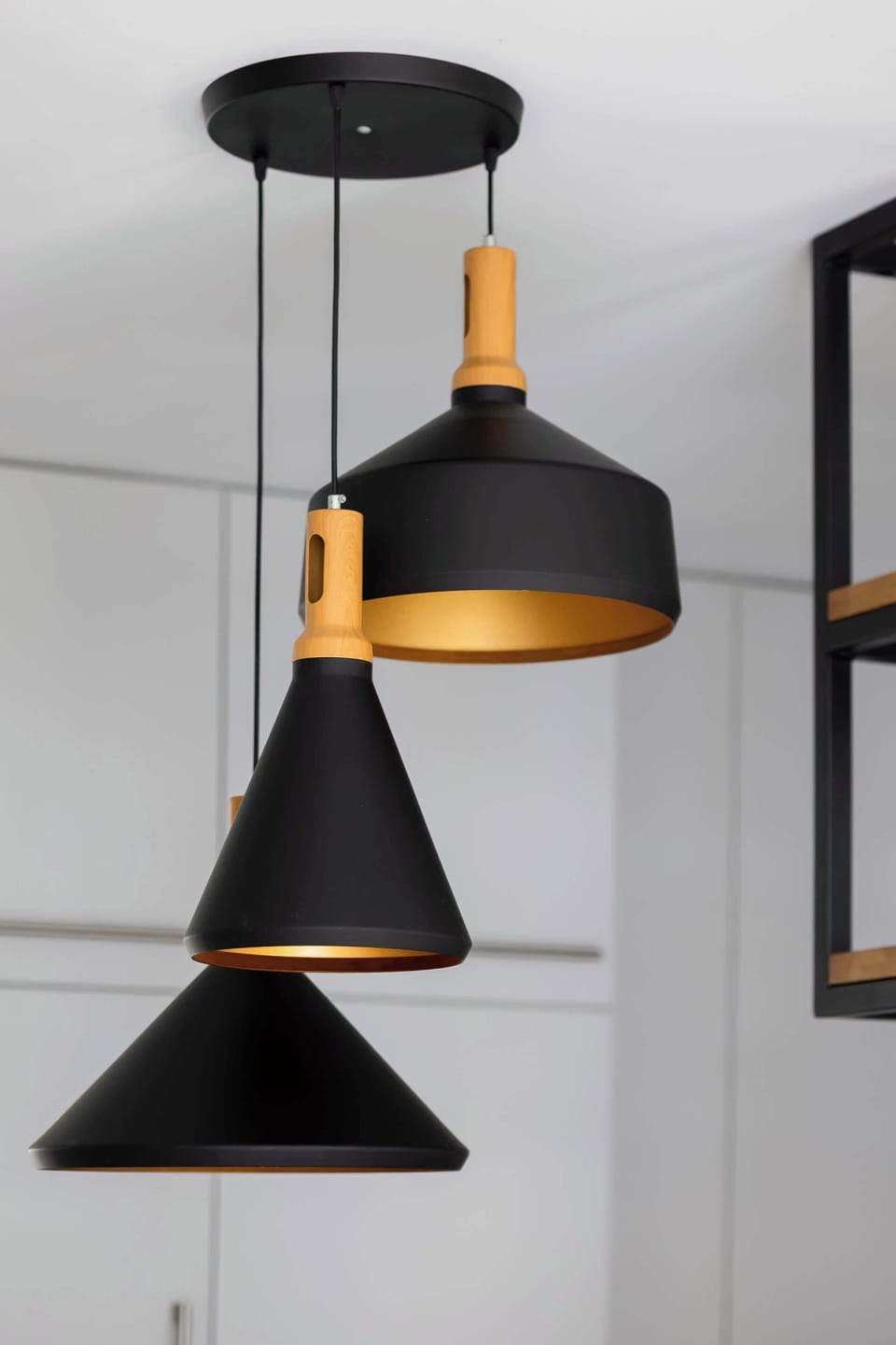 A set of modern black pendant lights hanging from the ceiling. The lights have a geometric, minimalist design. The background suggests a contemporary interior space.