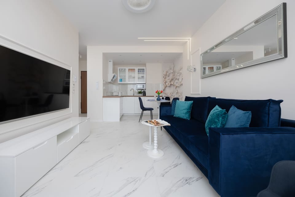 From this perspective, the living room reveals its polished marble-effect flooring and the expansive navy blue corner sofa.