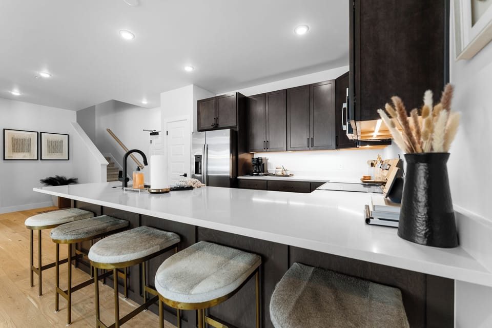 Full kitchen with stainless steel appliances, and a breakfast bar with seating for five.