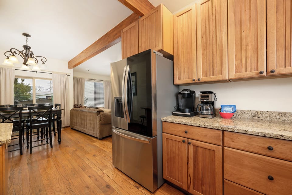 Your fully equipped kitchen at Granby Lake Shore Estates Townhome 5 features warm wood cabinets, granite counters, and stainless appliances—perfect for preparing meals during your stay.