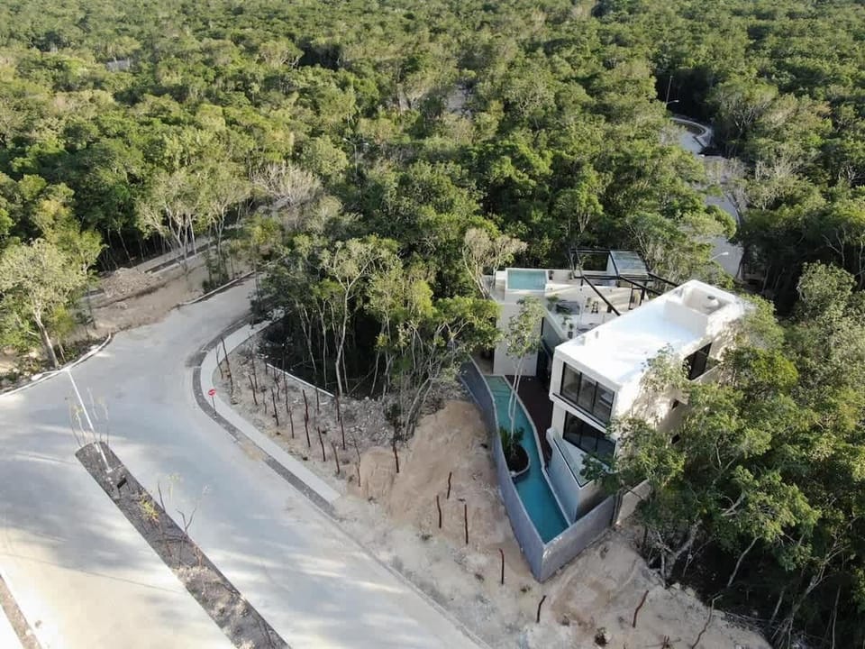 Aerial drone view of designer villa rooftop surrounded by Tulum jungle canopy.