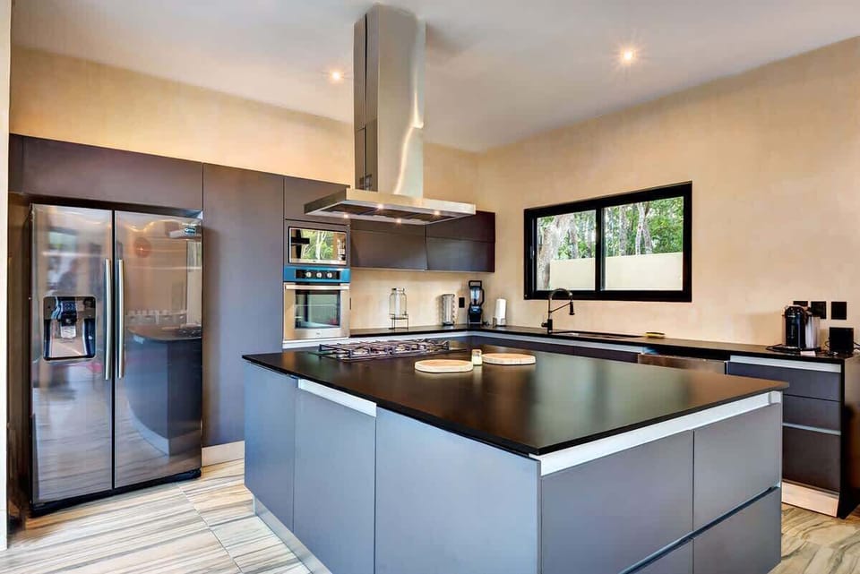 Gourmet kitchen with black granite island and premium stainless steel appliances.