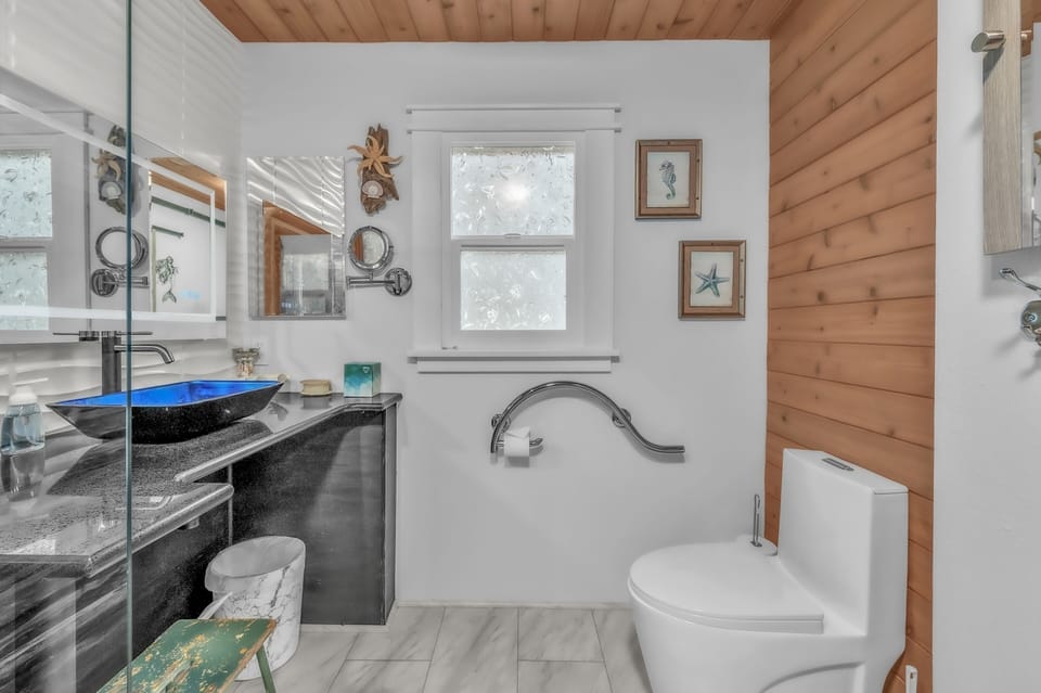 Refresh in your stylish bathroom featuring a sleek glass shower, modern vessel sink, and warm wood ceiling details.