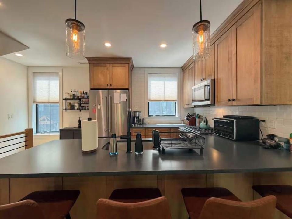 A wider view of the kitchen shows the full layout, with the dark countertops, stainless appliances, and peninsula seating all working together in an open, well-lit space.