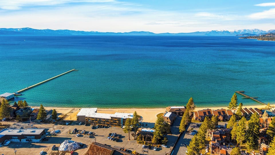 Wide view of the sandy beach and clear blue water.