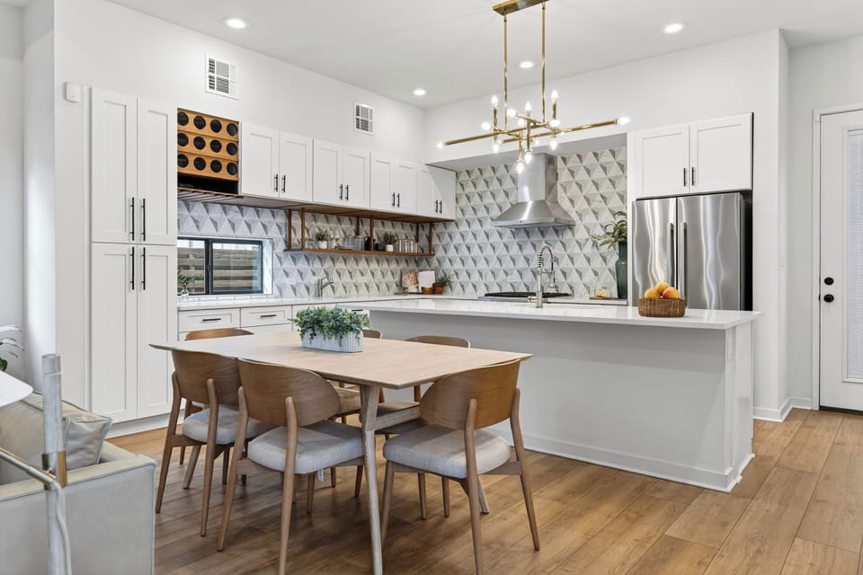 Sleek modern kitchen with statement tile, oversized island, and a dining setup made for gathering.