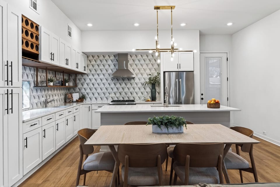 Sleek modern kitchen with statement tile, oversized island, and a dining setup made for gathering.