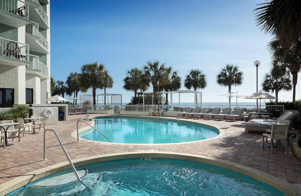 Dive into sunlit pools with ocean breezes steps away.