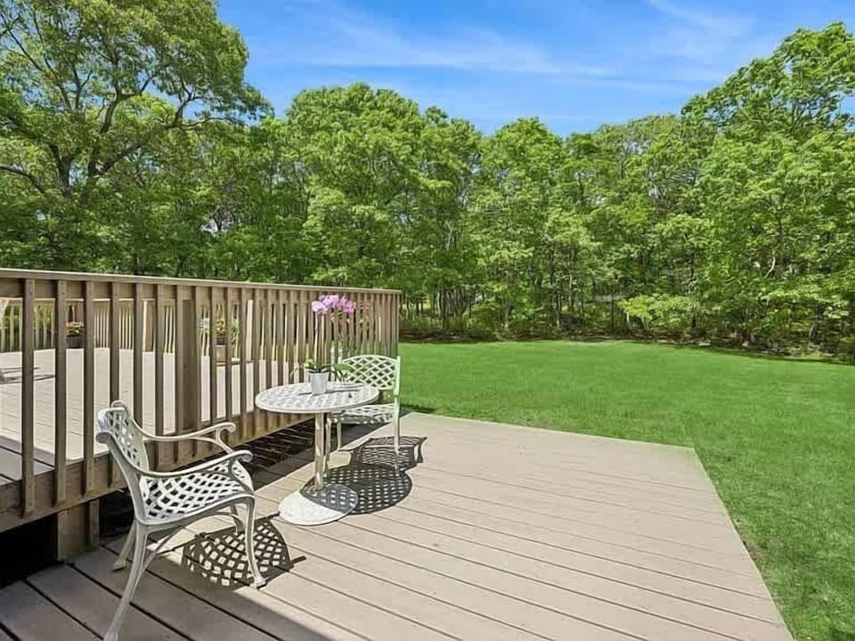 Expansive private backyard with deck and lush tree-lined lawn