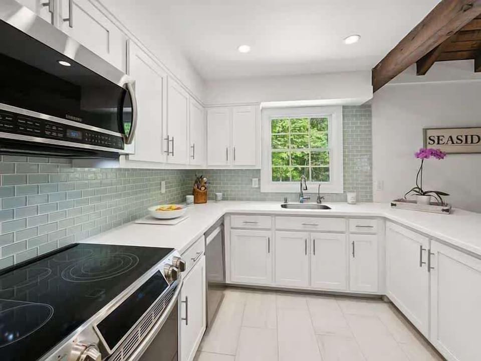 Renovated kitchen with sea-glass backsplash and quartz countertops