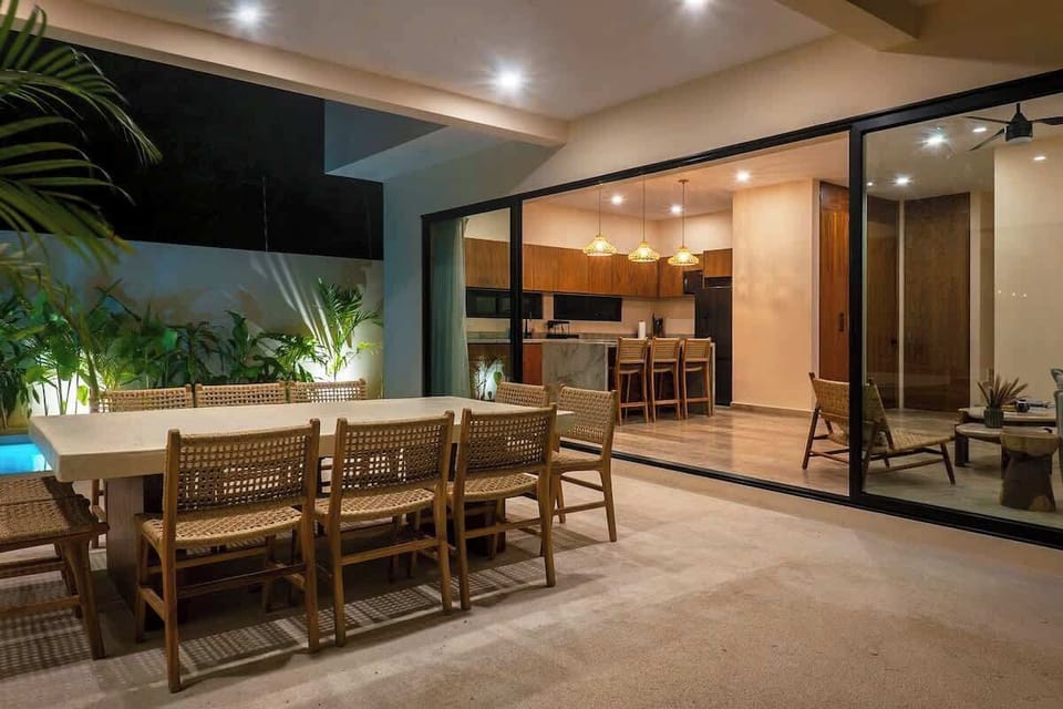 Beautiful outdoor dining area with lighting. Large windows connect to the interior of the villa.
