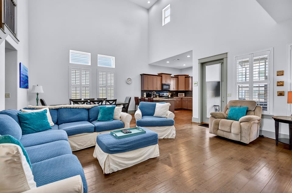 1st Floor - Spacious two-story great room with lounge seating and a 75” 4K Smart TV, perfect for gathering after a day at Miramar Beach. Open layout connects the living area, dining space, and chef’s kitchen—ideal for relaxing during your beach vacation.