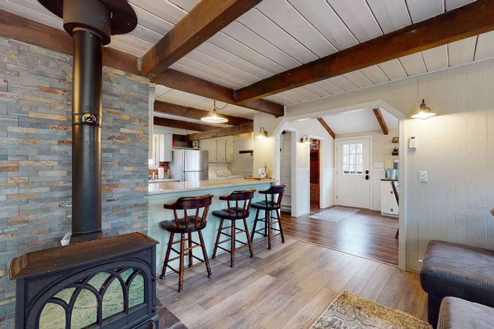 View from the living area into the kitchen and breakfast bar, highlighting the open-concept layout and wood stove centerpiece.