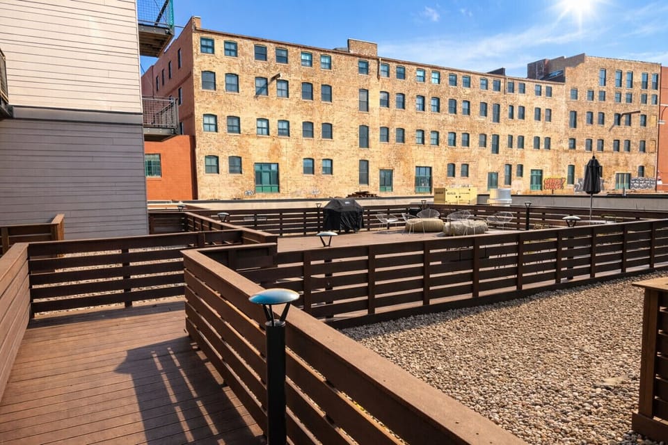 Spacious community roof deck featuring flexible seating areas, grill, and sun-soaked lounge areas—perfect for relaxing or entertaining with an urban backdrop