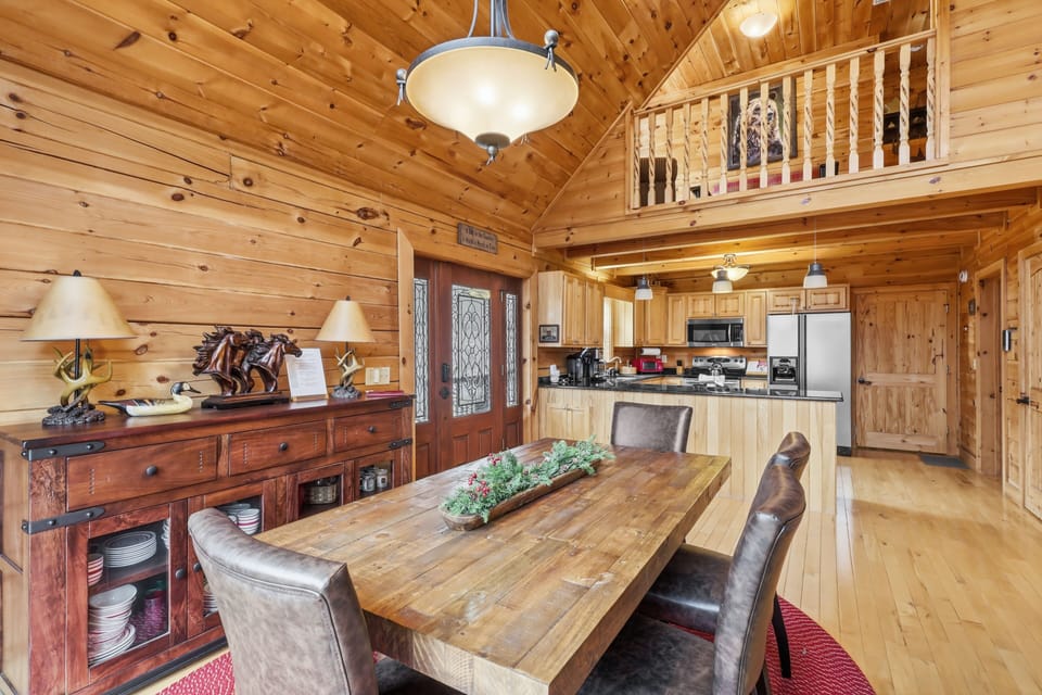 Dining area with rustic wood table, leather chairs, and open kitchen