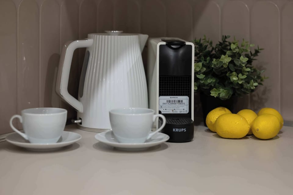 A close-up shot focuses on the welcome amenities, including a modern coffee machine, white ceramic cups, and a bowl of fresh lemons. These thoughtful details emphasize the host's commitment to guest comfort and quality.