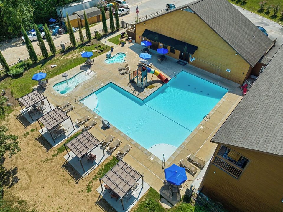 Resort style pool with waterslide, hot tub, and plenty of seating.
