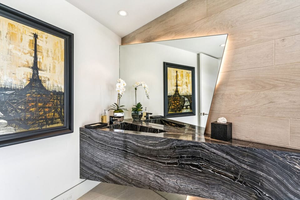 Modern powder room w/ stone vanity, statement mirror & warm lighting