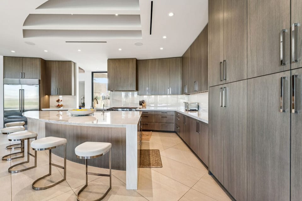 Modern kitchen w/ long counters, integrated appliances & casual seating