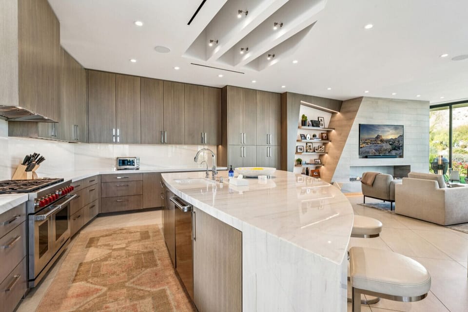 Sleek kitchen w/ large curved island & bar seating, ideal for cooking & gathering