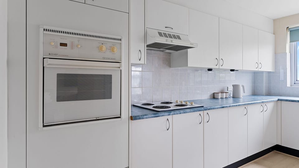 Fully equipped kitchen with oven, cooktop, and ample storage