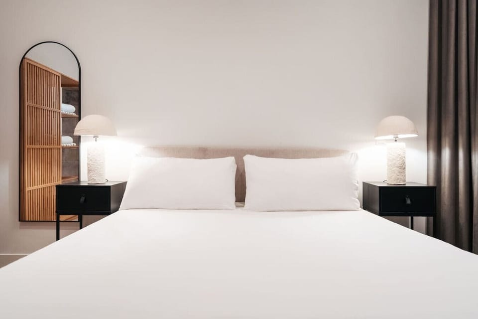 Sink into a plush king-size bed with soft lighting and a calm, modern ambiance.