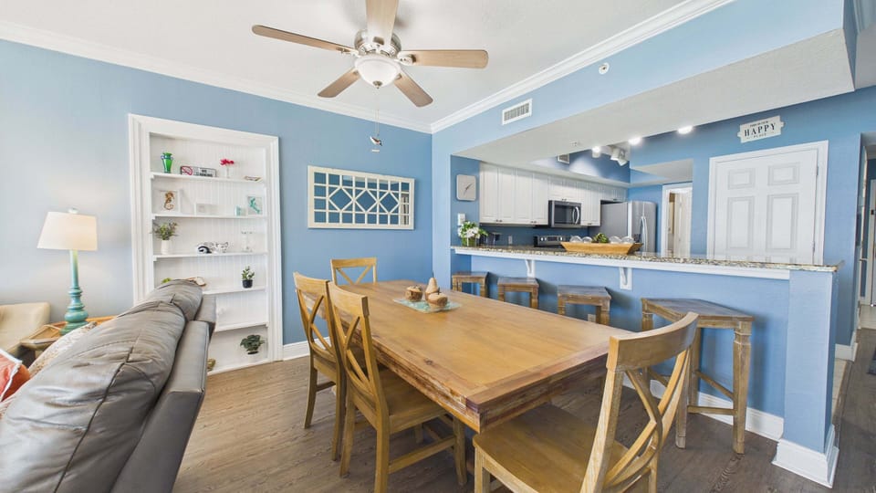 Dining table and kitchen with coastal decor shimmering throughout the unit