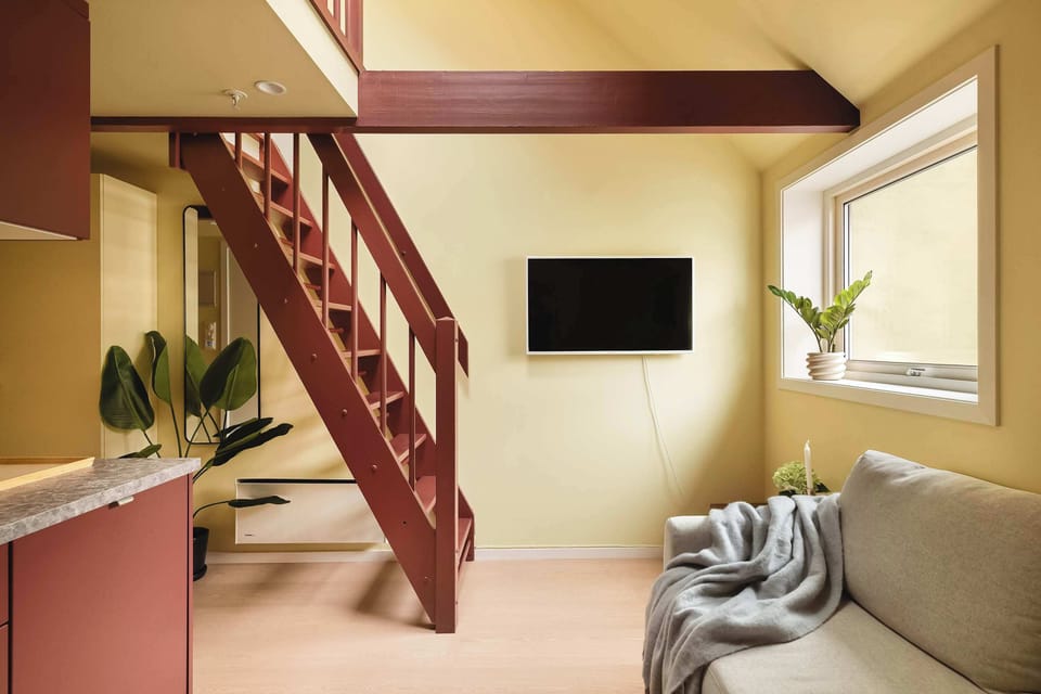 A bright and cleverly designed living space with a cozy sofa corner and TV — perfect for relaxing after a day in Bergen. The ladder-style staircase adds character and leads up to the loft.