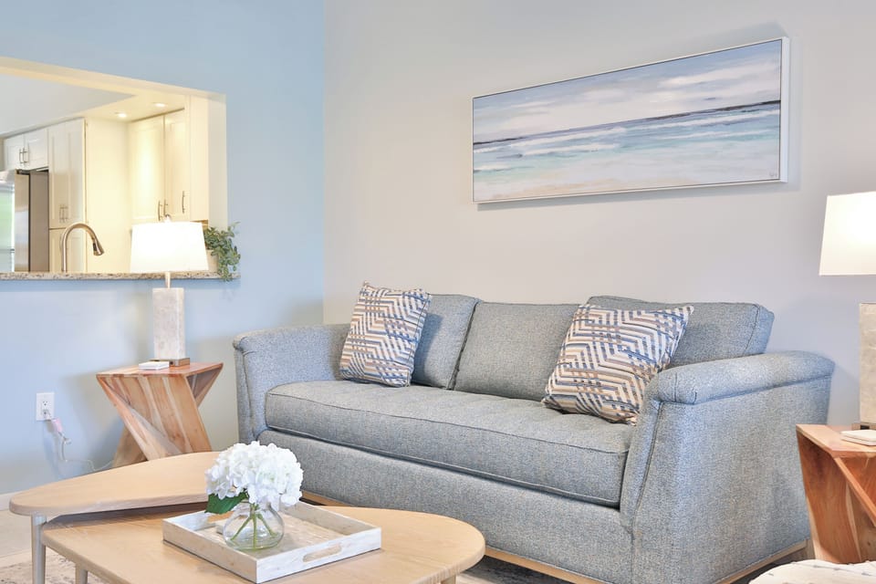 Sink into the plush gray sofa where coastal artwork and soft lighting create your perfect retreat after beach days.