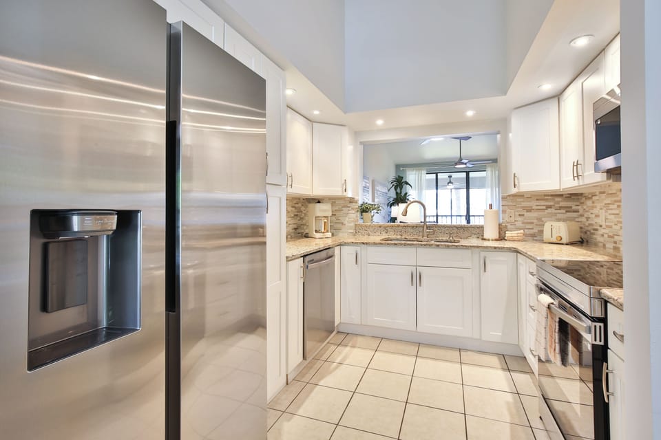 Your spacious chef's kitchen features gleaming stainless steel appliances, granite countertops, and elegant white cabinetry with beautiful tile backsplash—perfect for preparing memorable meals together.