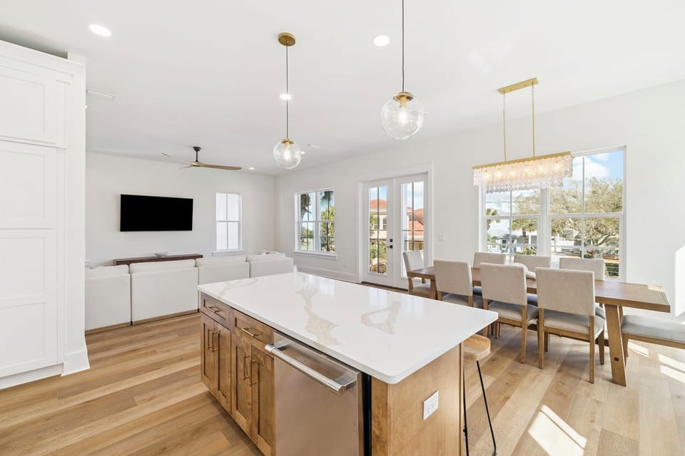 Your bright, modern kitchen flows seamlessly into the dining area, where natural light pours through large windows as you prepare meals and gather around the elegant table.