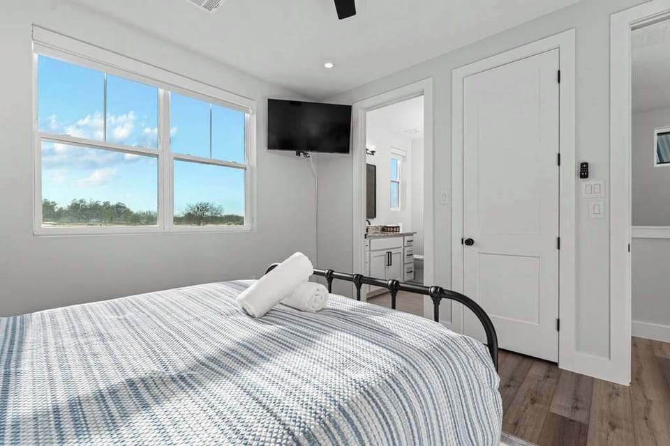 Queen bedroom with TV & bright window views.