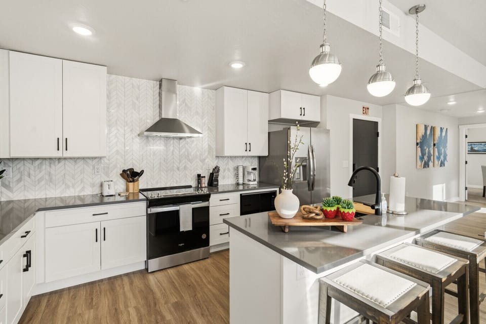 Modern kitchen with island seating, stainless steel appliances, and bright lighting