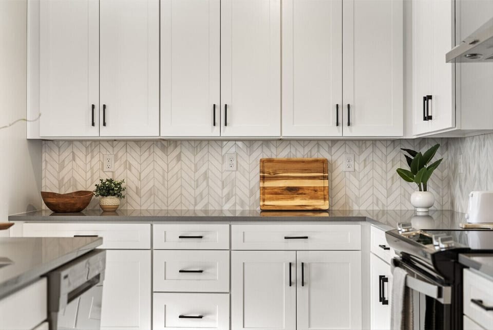 Bright kitchen with white cabinetry, sleek counters, and patterned tile backsplash