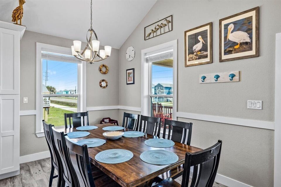 Dining table with seating for large groups, surrounded by windows providing natural light and coastal views.