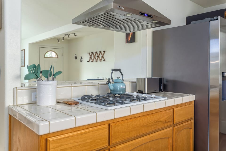 Kitchen is stocked with cooking utensils, pots and pans, baking sheets, toaster.