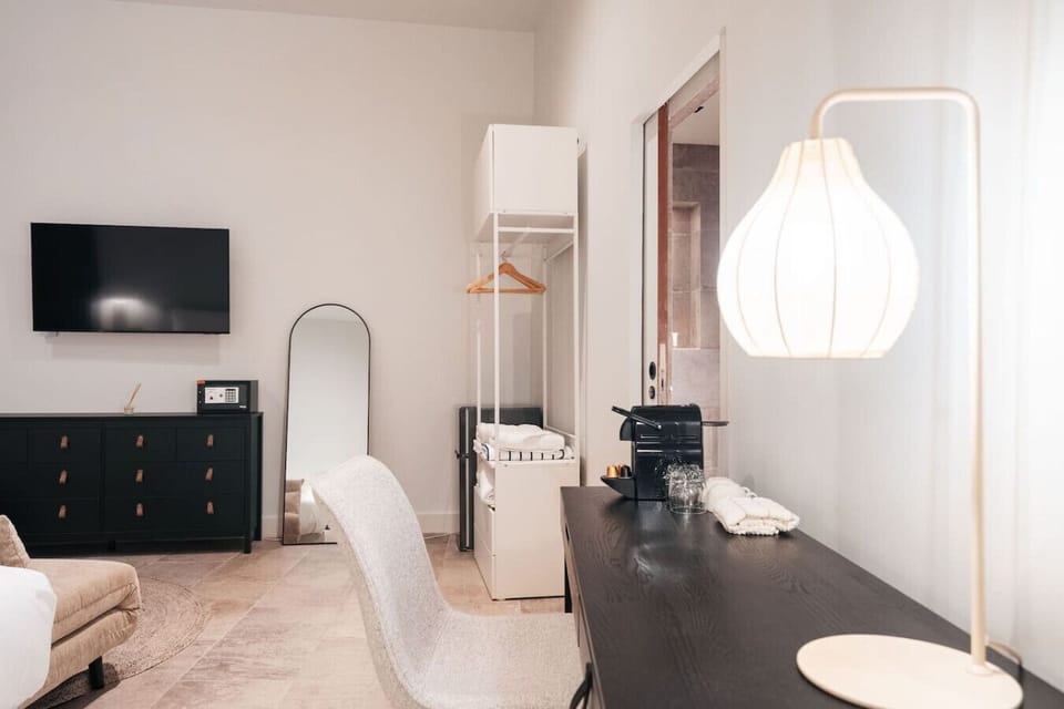A clean, modern space with a work desk, in-room coffee, and a wall-mounted TV—everything you need for a comfortable and convenient stay.
